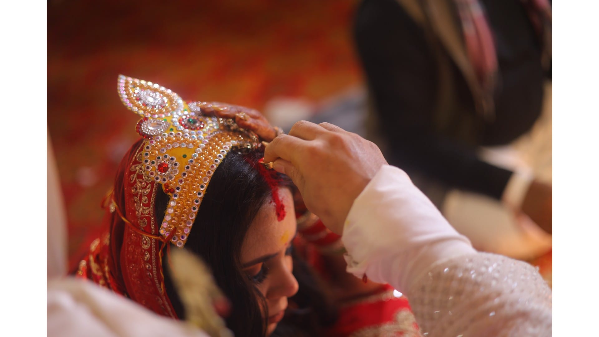 Groom applying sindoor to the bride during a traditional Indian wedding ceremony.